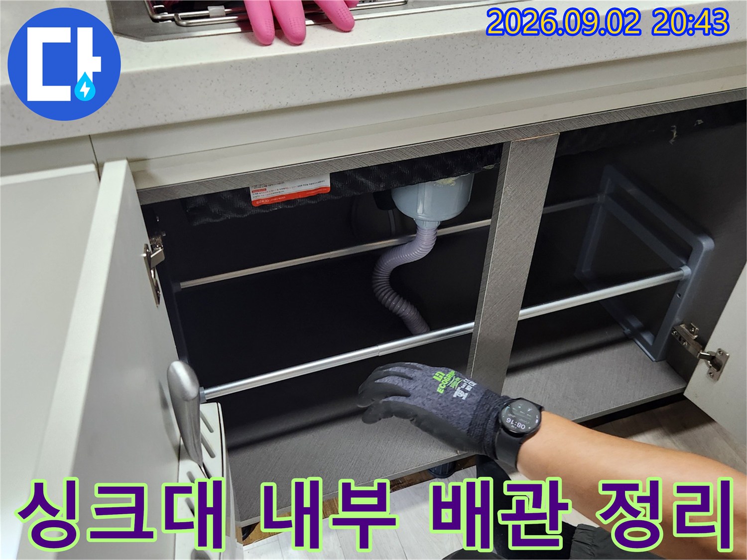 정리된 싱크대 하부장의 배수 호스와 선반 구조물