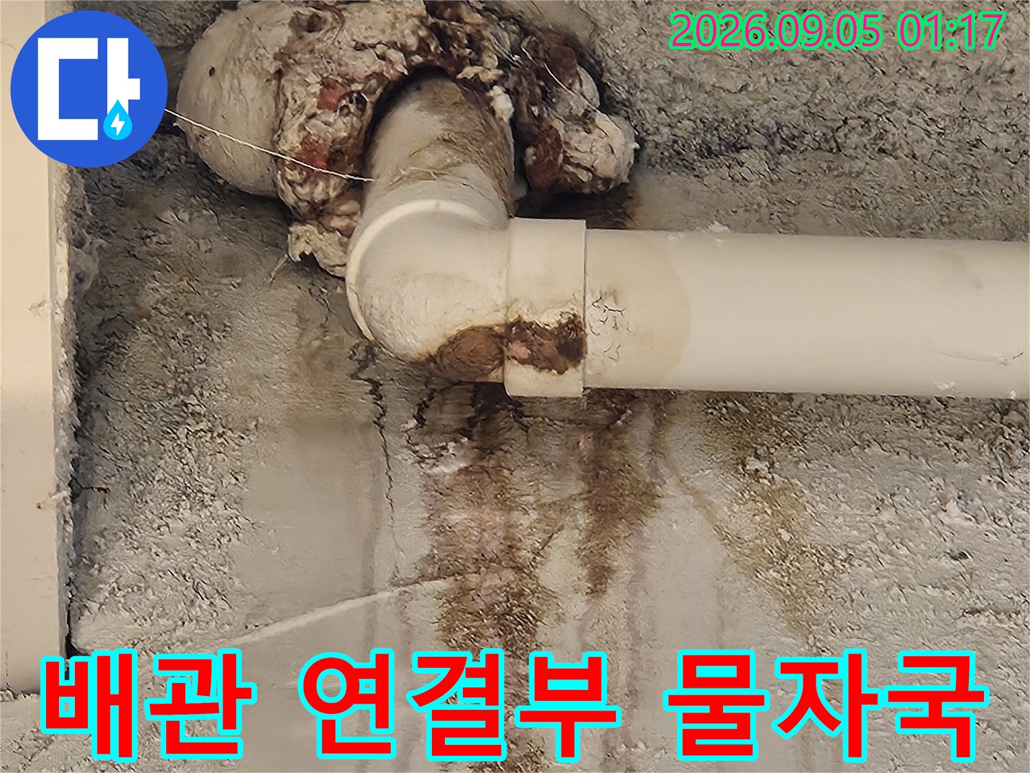 배관 연결 부위와 벽면 사이에 발생한 짙은 누수 흔적과 습기