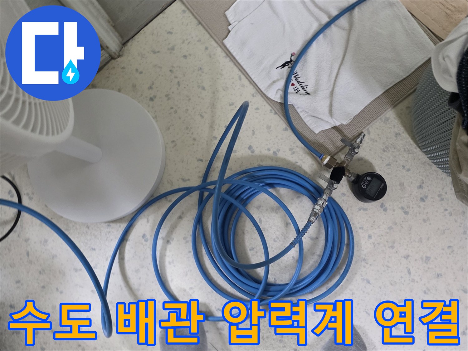 파란색 호스로 연결된 수도 배관 압력 측정 장치