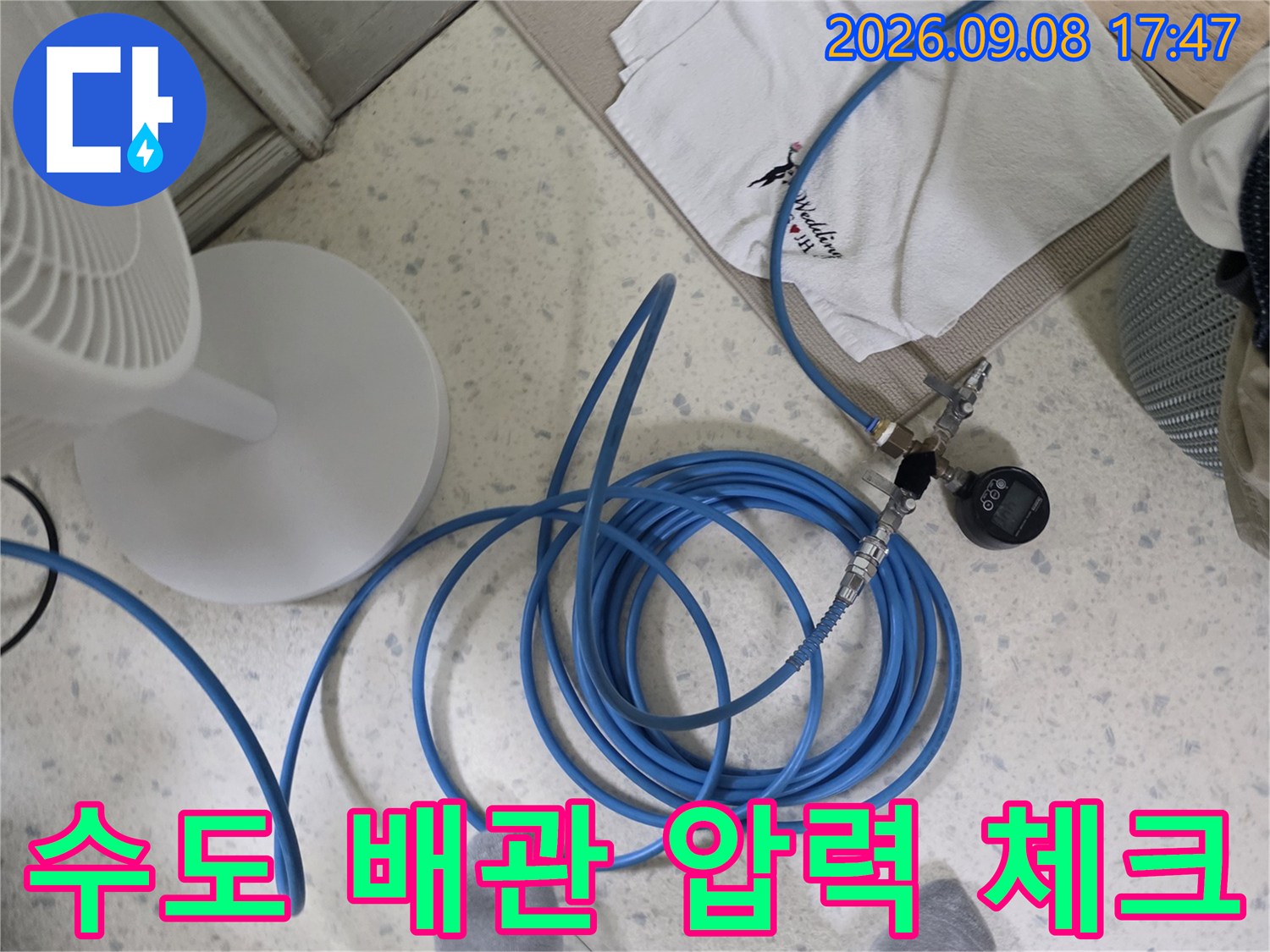 파란색 호스와 연결된 압력계로 진행하는 배관 점검 작업