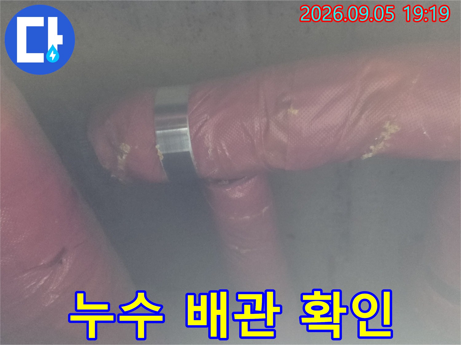 분홍색 보온재가 씌워진 천장 배관을 육안으로 검사하는 사진입니다.