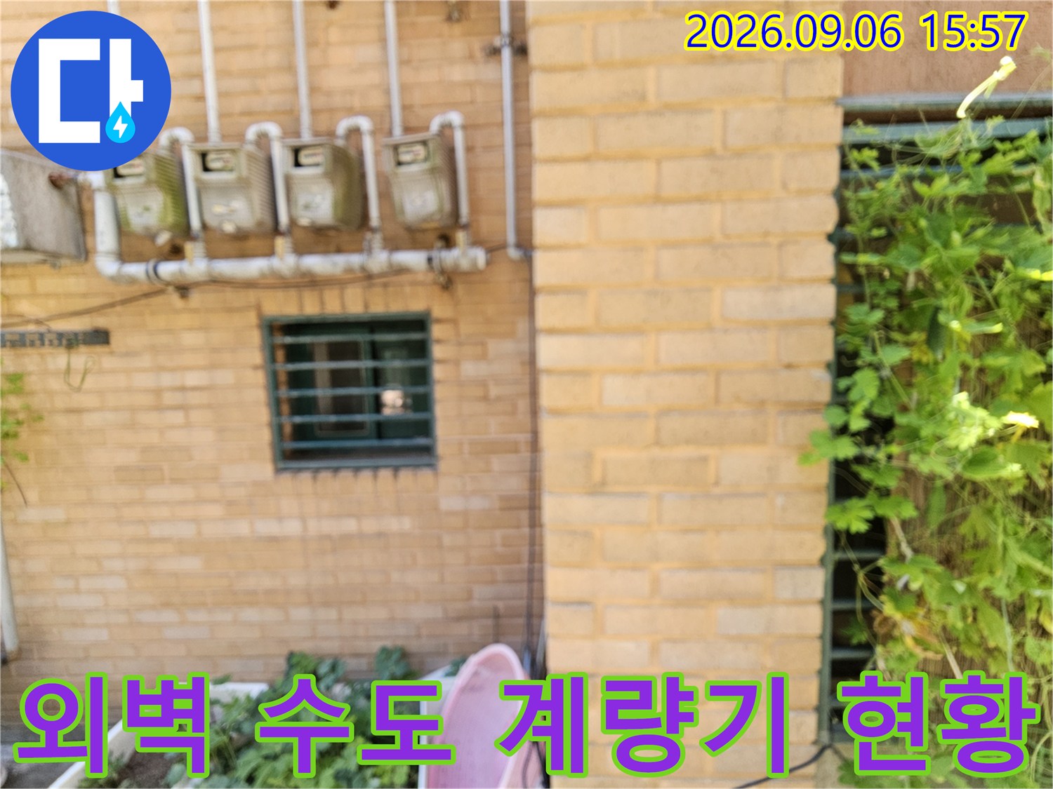 빌라 외벽 벽돌면의 수도 계량기와 연결된 수직 배관 구조