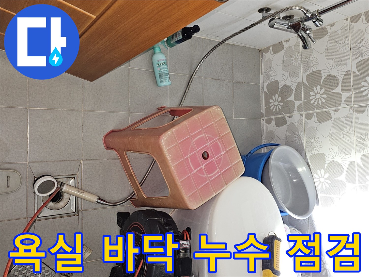 화장실 배수구 옆에 놓인 누수 진단용 압력 측정기와 공구들