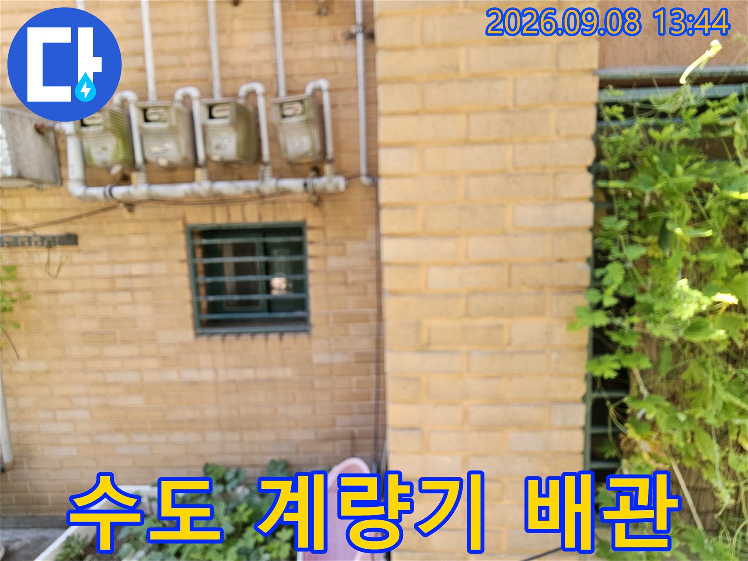 벽돌 벽면에 설치된 여러 개의 수도 계량기와 연결 부위 상세 모습입니다.