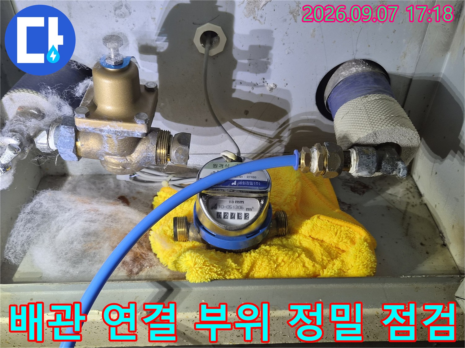 수도 계량기와 파란색 압력 호스가 연결되어 작동 중인 배관 모습입니다.