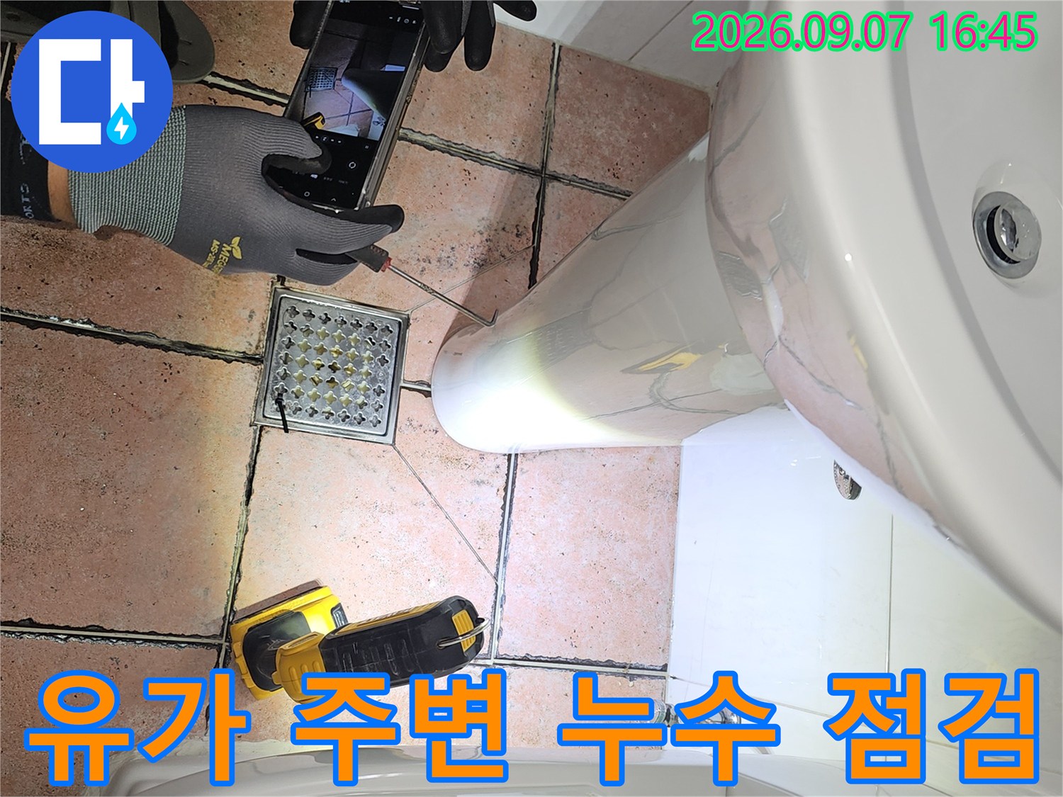작업자가 장갑을 끼고 스마트폰으로 배수구 유가를 촬영하는 모습입니다.