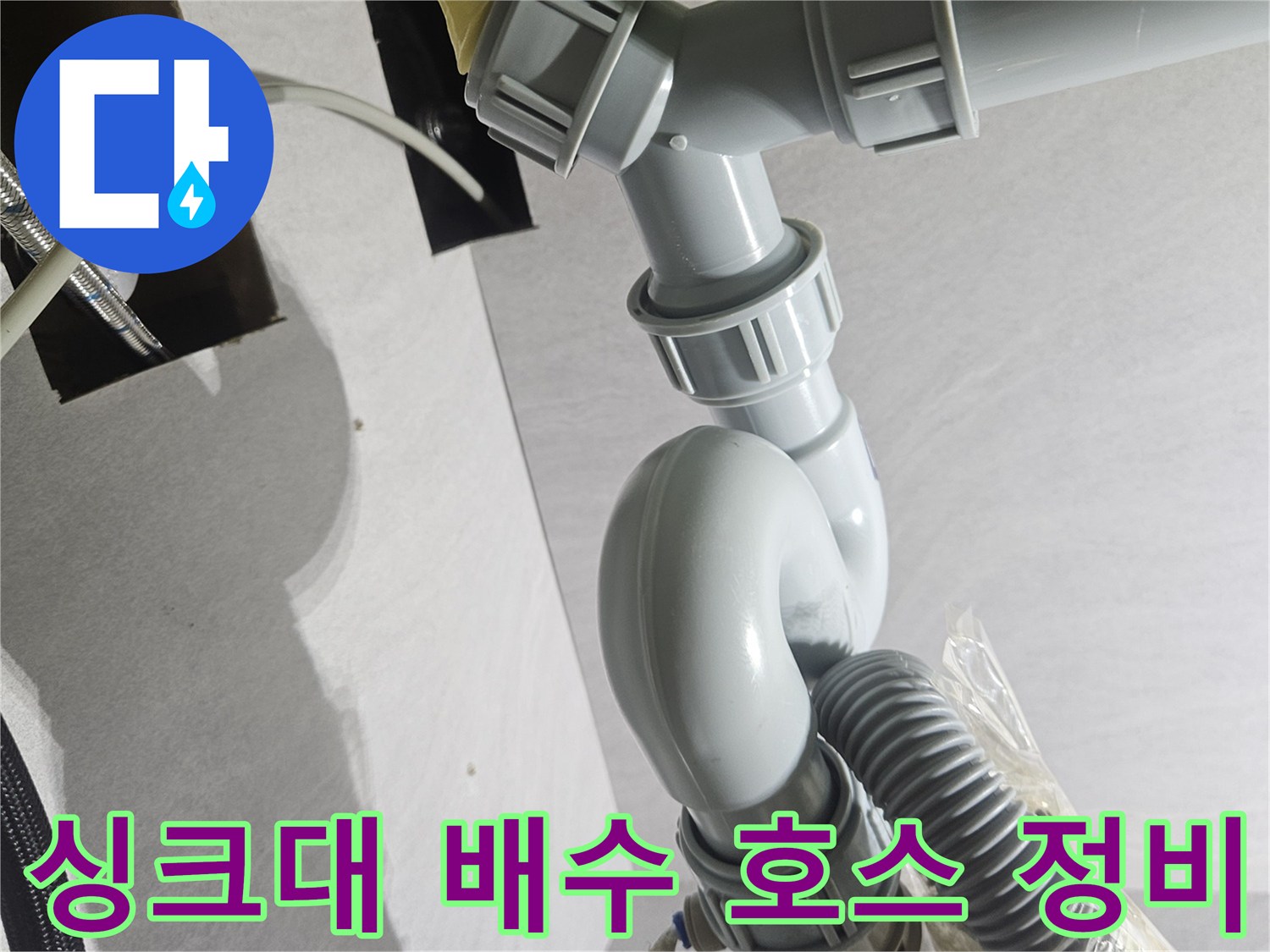 정상적인 연결을 위해 재조립된 싱크대 하부의 회색 배관 구조-누수 방지 조치