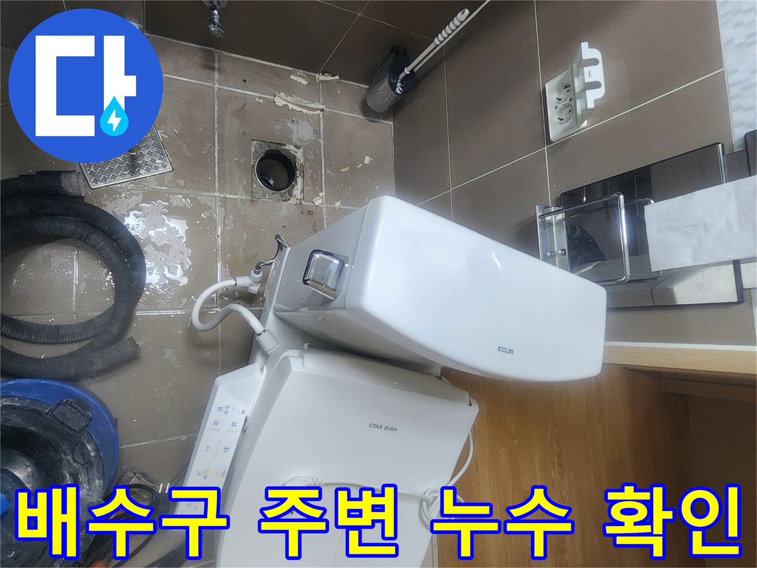 변기 아래쪽 배수구 근처에 고여 있는 물과 젖은 타일 모습