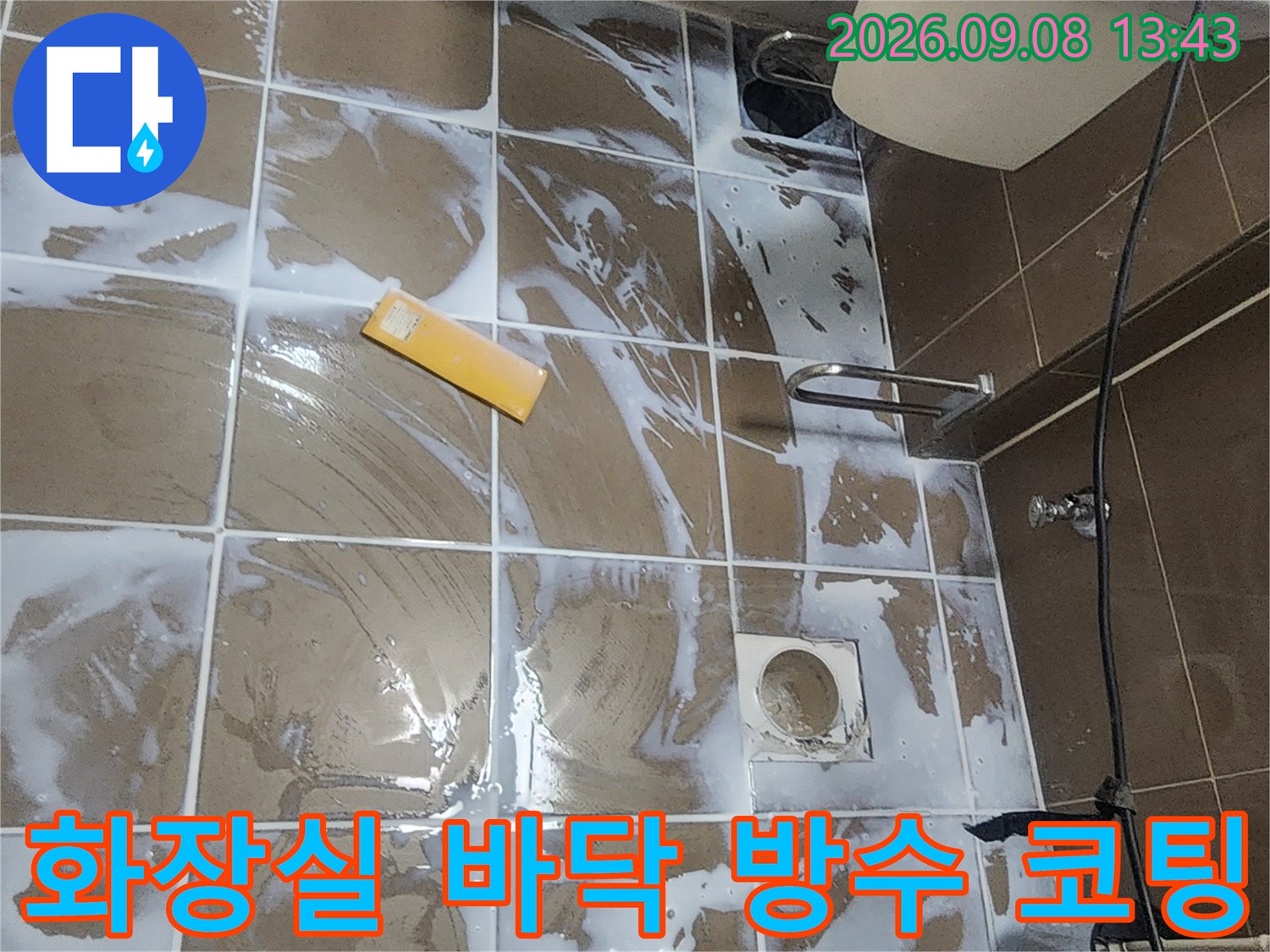 타일 표면에 하얀색 액체로 방수 처리를 하는 작업 현장입니다.