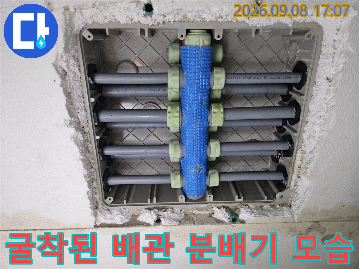 회색 배관과 파란색 분배기가 연결된 굴착 현장 사진