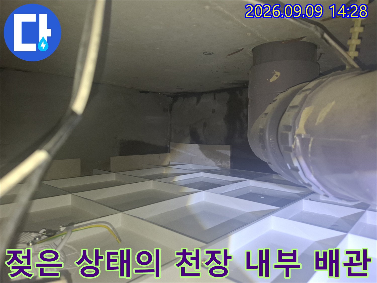 배관 주변에 물기가 스며든 흔적과 어두운 오염 부위입니다.