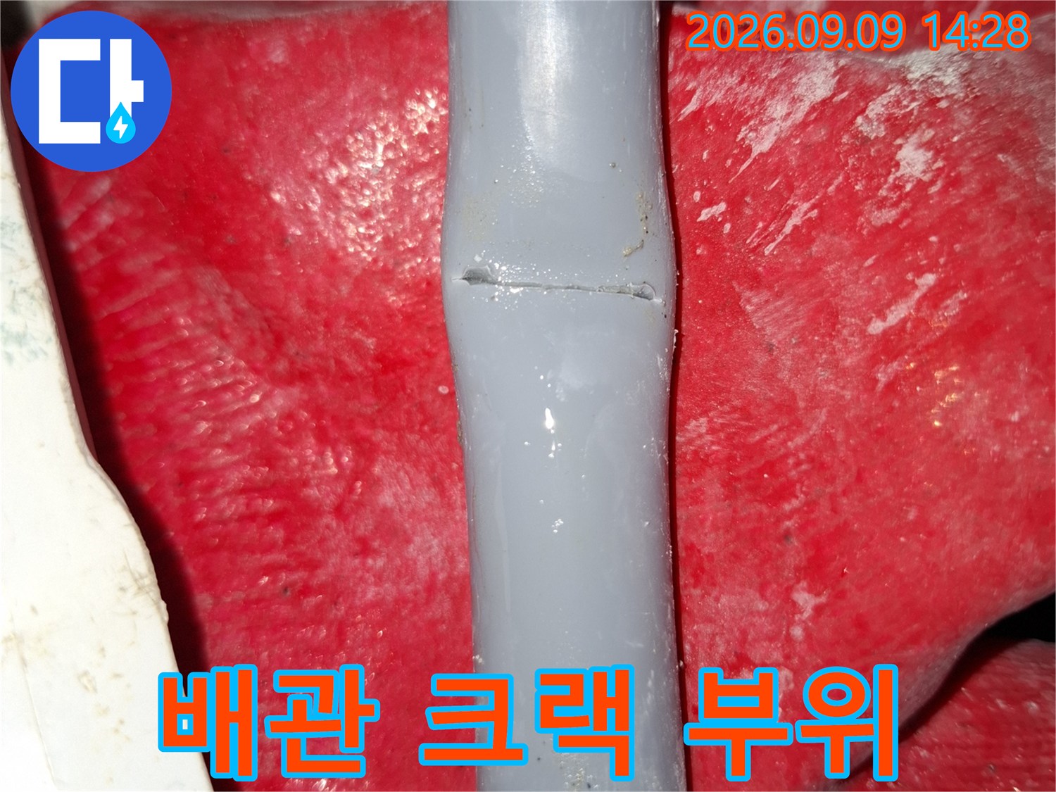 회색 수도 배관에 발생한 선명한 균열 모습입니다.