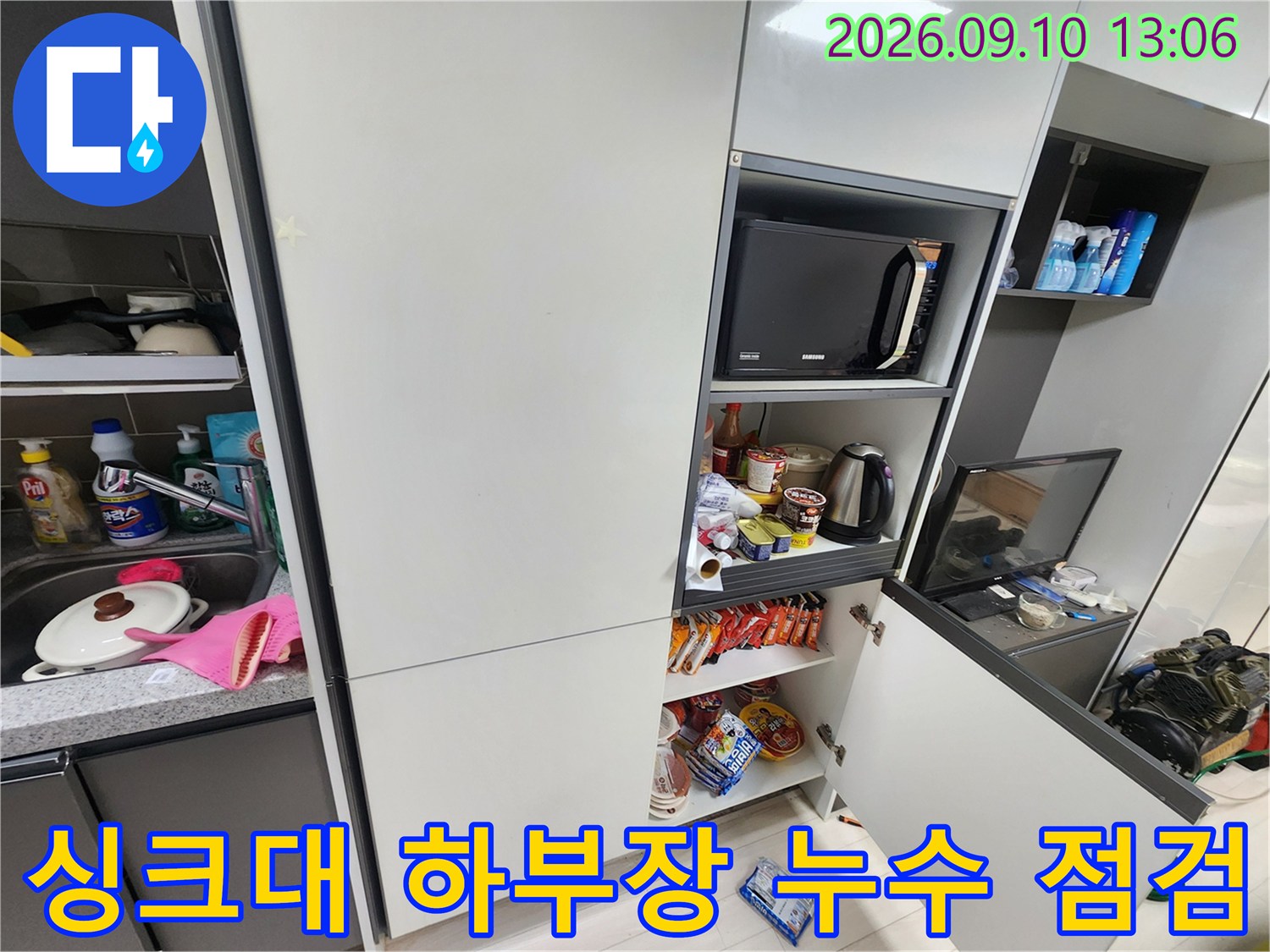 주방 수납장 내부의 전자레인지와 배관 주변 공간을 보여주는 사진입니다.
