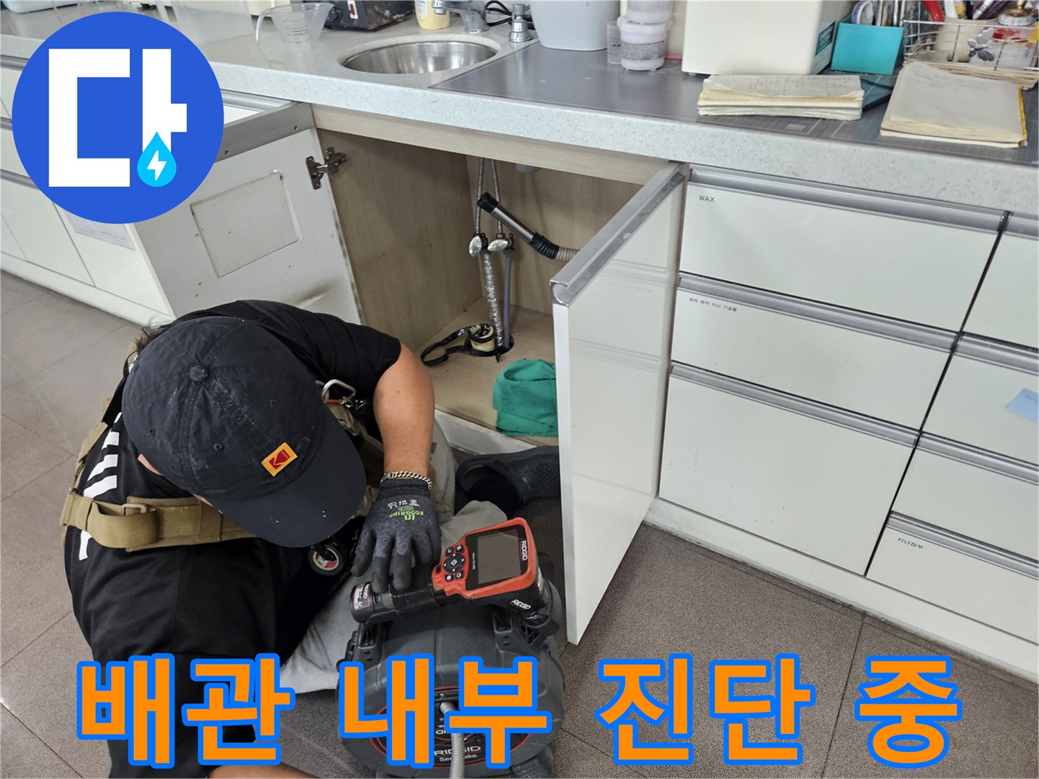 세면대 하부의 복잡한 배관 구조를 내시경과 압력계로 정밀하게 점검하고 있습니다.