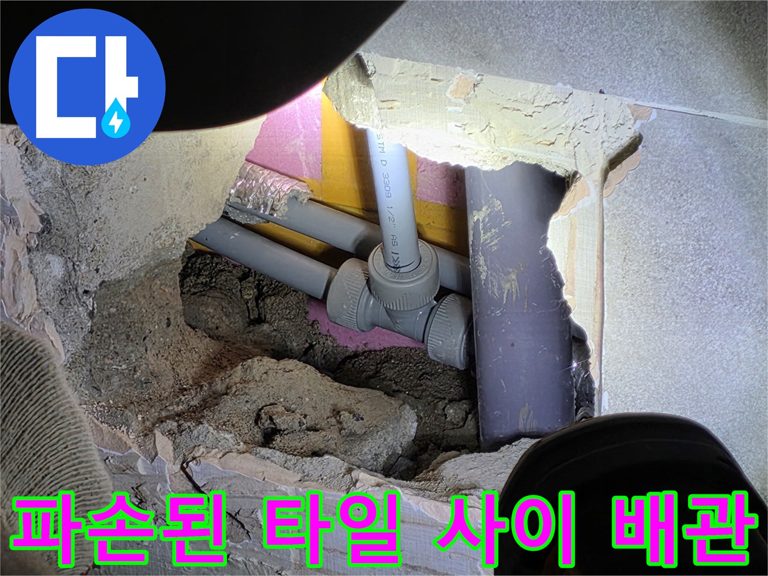 깨진 타일 틈새-드러난 매립 배관과 주변 구조물