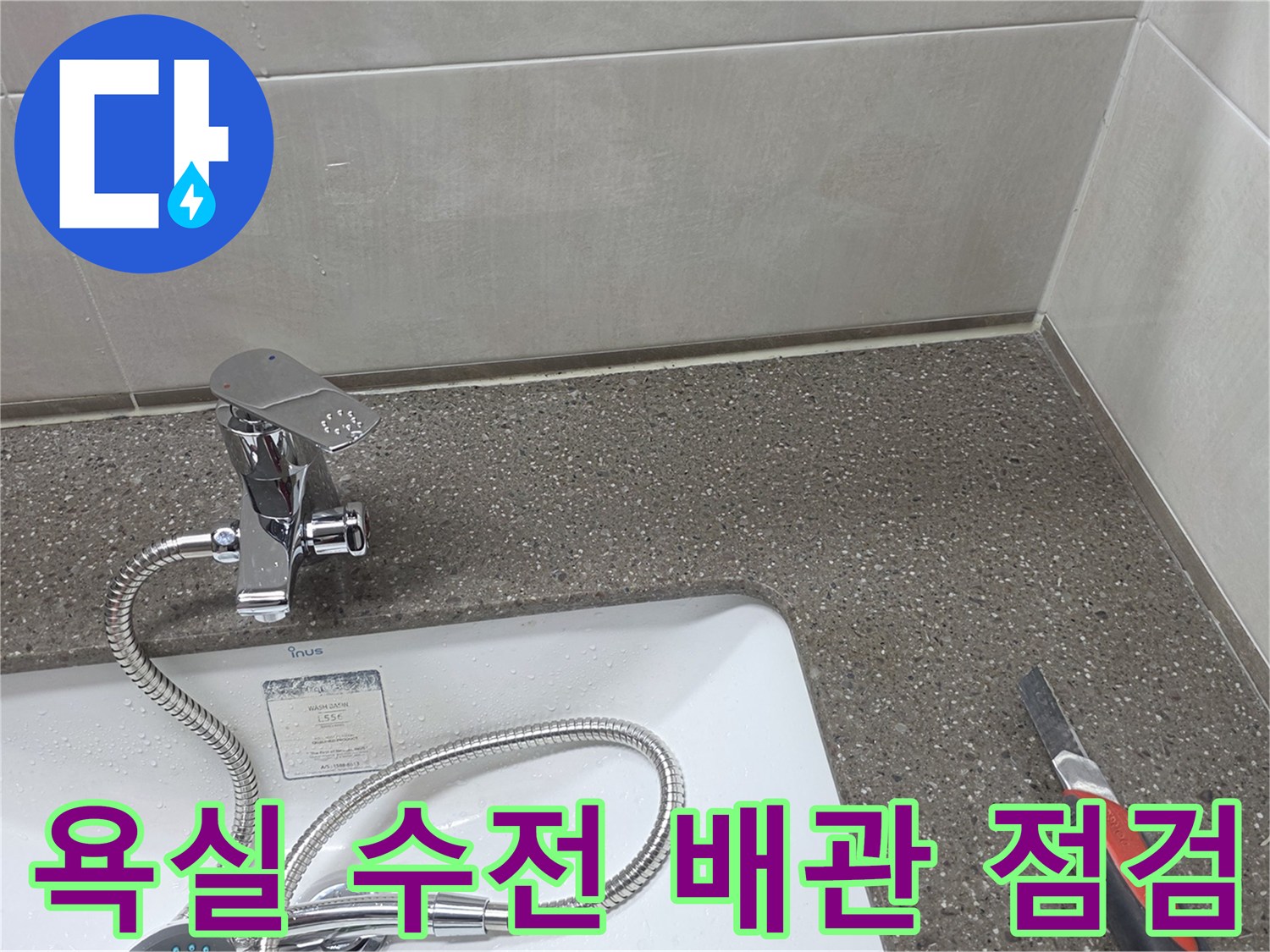 세면대 수전 아래 급수 호스와 타일 벽면 모습