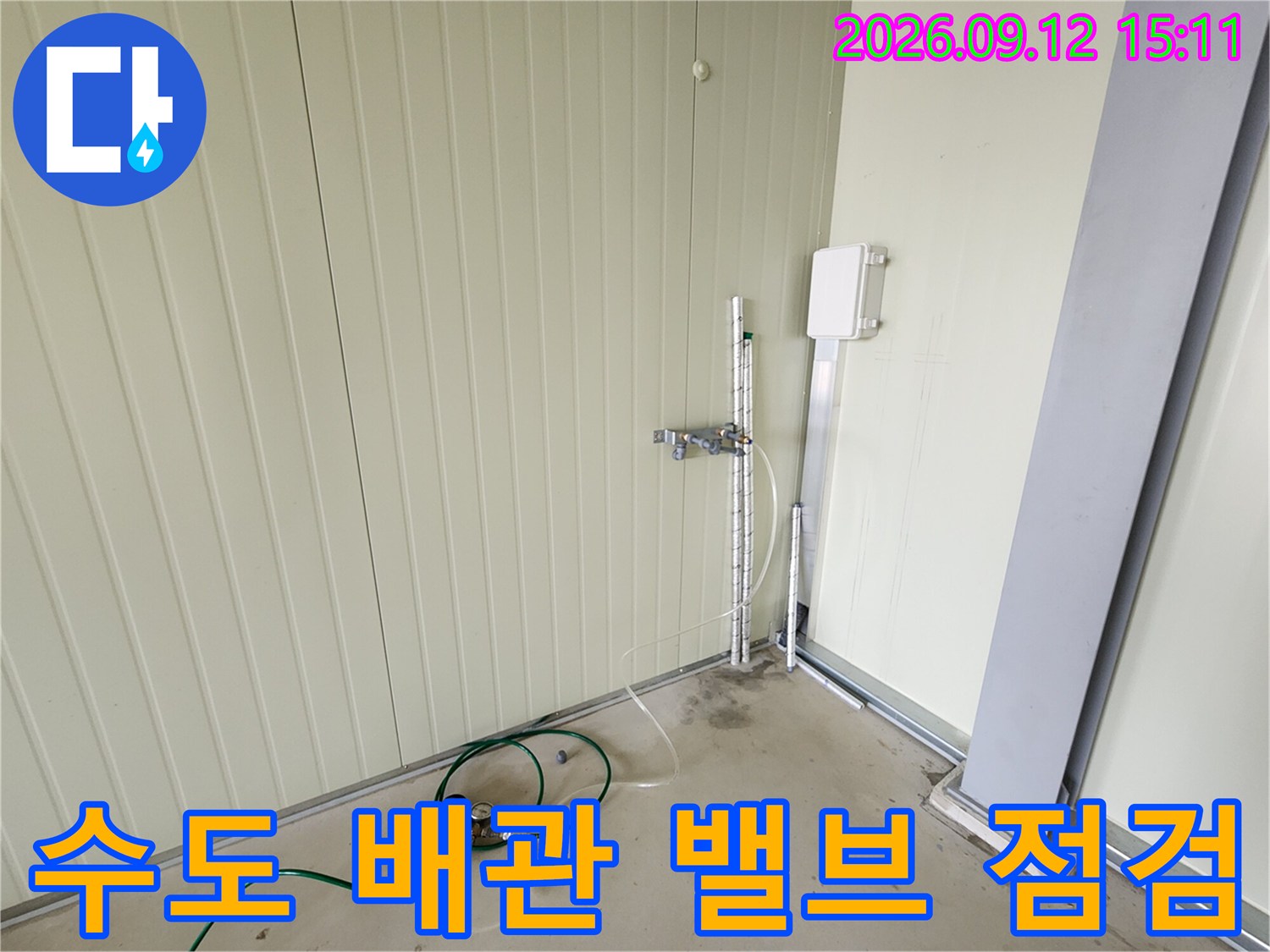 벽면에 설치된 금속 수도 밸브와 연결 배관의 근접 촬영
