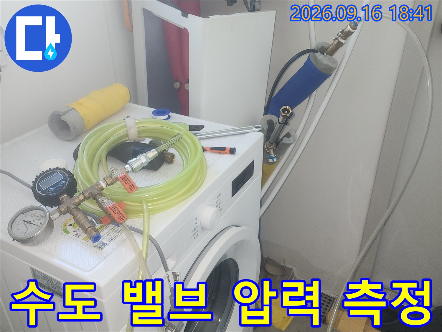 세탁실 수도 꼭지에 연결된 누수 탐지용 호스와 압력 게이지