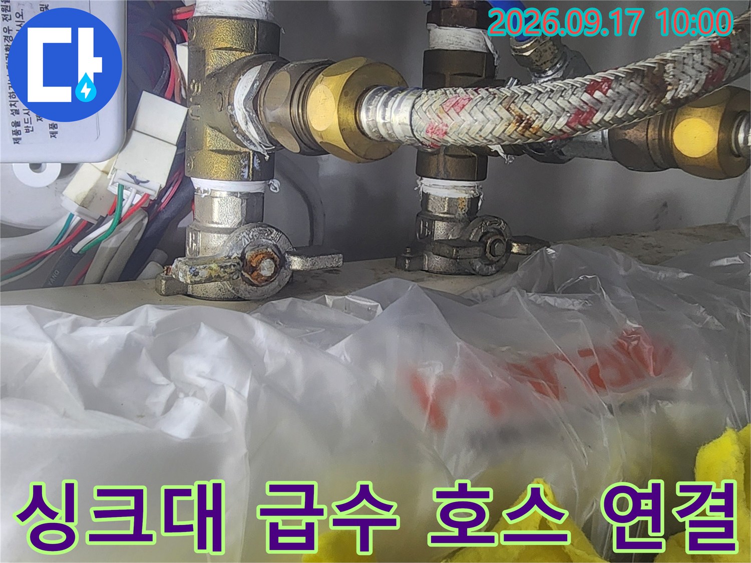 파란색과 노란색 급수 호스가 연결된 싱크대 하부 배관