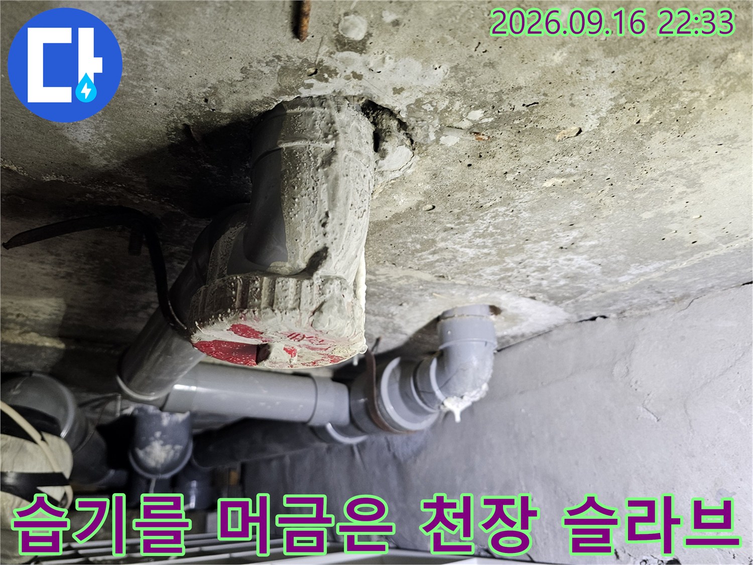 천장 점검구 내부에 노출된 배관과 젖어 있는 콘크리트 면