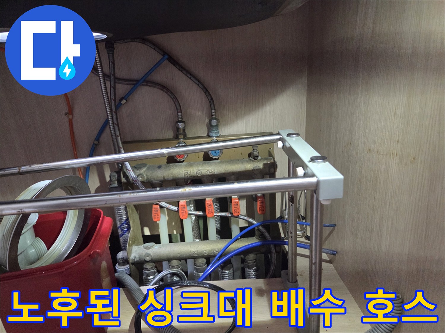 싱크대 하단에 복잡하게 얽힌-배수 호스와 급수 밸브들